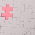 Close-up of an unfinished puzzle with a pink missing piece, highlighting emptiness.