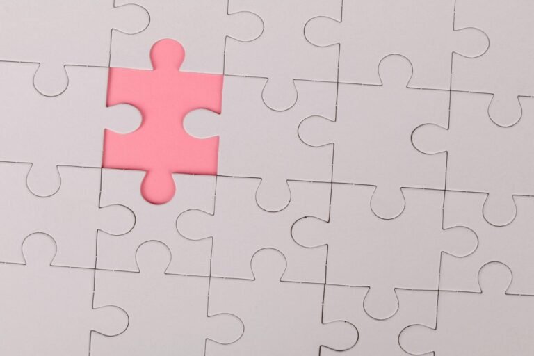 Close-up of an unfinished puzzle with a pink missing piece, highlighting emptiness.