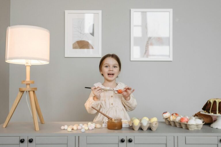 A child joyfully paints Easter eggs indoors, surrounded by lamps and art.