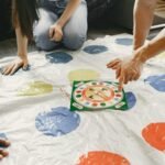 Hands on a colorful mat game with a spinner at the center. Fun and interactive play.