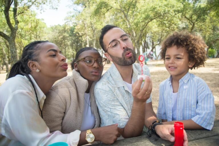 A joyful family bonding moment outdoors in a sunny park, blowing bubbles together.